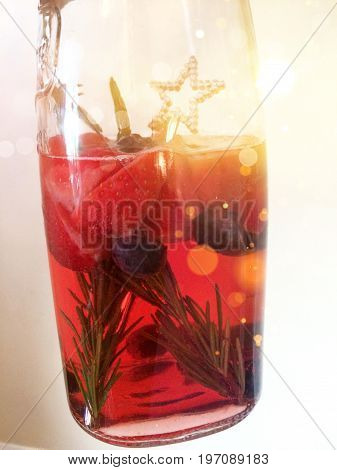 Jug of summer cocktail with strawberries, rosemary and blueberries