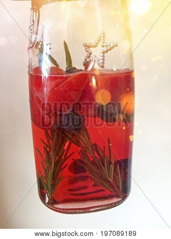 Jug of summer cocktail with strawberries, rosemary and blueberries