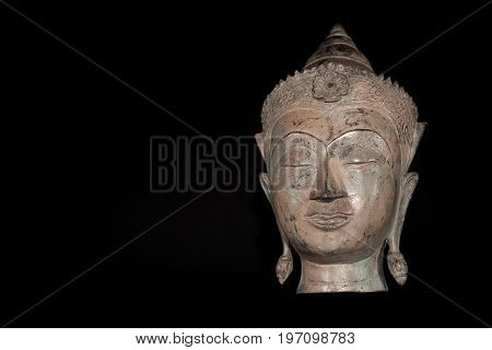 Buddha head. Classic traditional zen buddhism statue isolated against black background. Spiritual enlightenment expressed in a serene comtemplative expression.