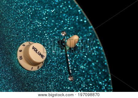 Turn up the volume. Control knob from a sparkly glam rock guitar. Loud music and fun party connotations.