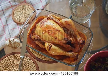 Fresh whole roasted chicken with garlic in glass form for baking. Home dinner concept