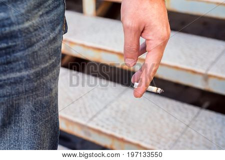 Smoking concept man's hand holding a cigarette close up