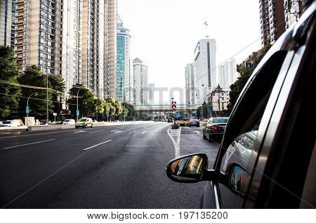 Car makes its way down a Chinese highway in Shanghai, amidst high rise offices and apartment blocks