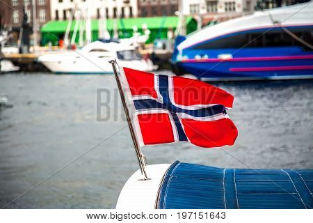 Norwegian flag flying in the wind over the sea on heavy foggy day in Northern Norway