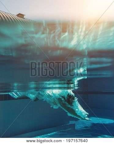 Man is jumping into the swimming pool. Man is swimming under water in swimming pool.