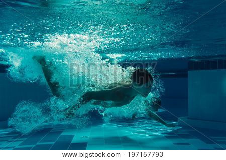 Men are jumping into the swimming pool. Men are swimming under water in swimming pool.