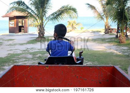 Asian boy learned to drive a truck on the beach at Samui island Thailand.