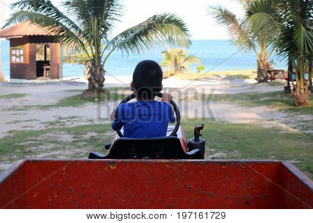 Asian boy learned to drive a truck on the beach at Samui island Thailand.