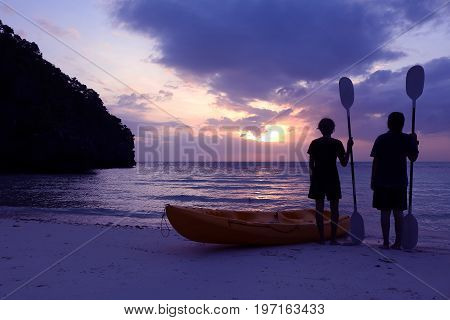 Silhouette kayaking on the beach with tourist girl looking blue sky sunset.
