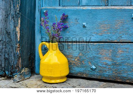 Lavender in a yellow kouvinum on a background of blue shabby door
