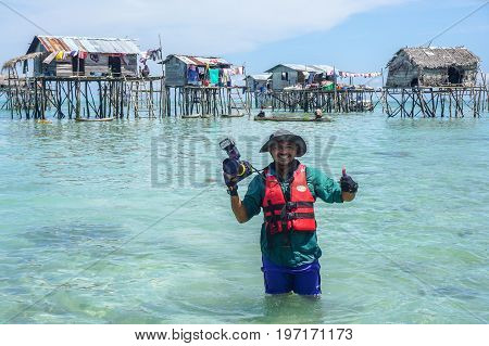 Semporna,Sabah,Malaysia-Apr 23,2017:Happy traveler man photographer with professional camera at floating village in Bodgaya island in Semporna,Sabah,Borneo,Malaysia.