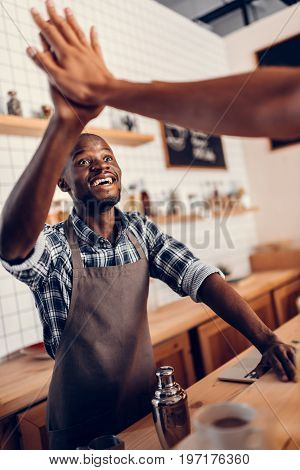 African American Barista Giving Highfive To Client In Coffee Shop