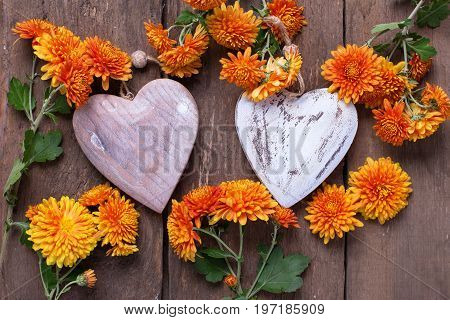Fresh orange autumnal flowers chrisanthemum and heart on retro wooden background. Selective focus. Top view.