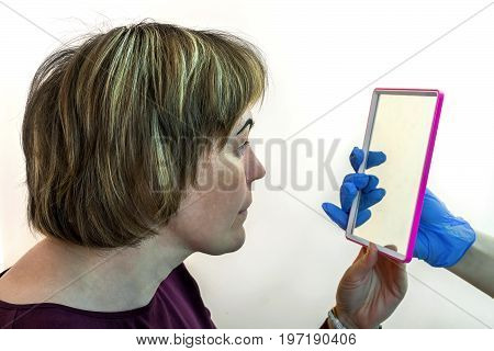 Eyebrow correction. Correcting the form. Drawing of a line of eyebrows in a beauty salon. A female patient looks in the mirror.