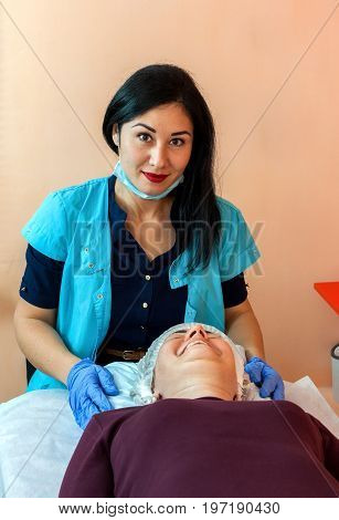 The cosmetologist with the patient in beauty salon. Preparation for the procedure. Facial care.