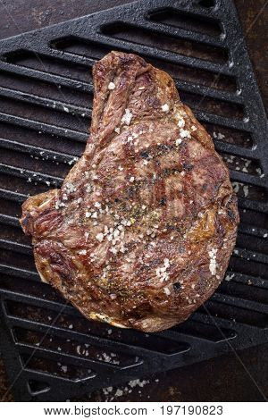 Barbecue dry aged Rib of Beef with salt and pepper as top view on a grillage 