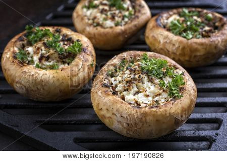 Traditional Italian Mushroom Caps stuffed with Feta as close-up on a grillage 