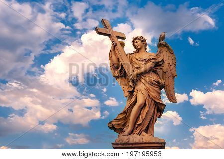 Marble statue of Angel with the Cross at sunset, one of the ten angels on Saint Angel Bridge, symbols of Christ's Passion, Rome, Italy