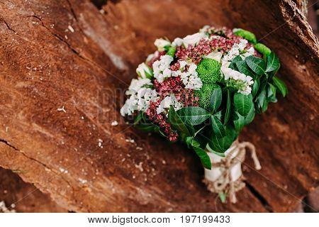 Rustic wedding bouquet with different flowers and greens on wooden background. Top view.