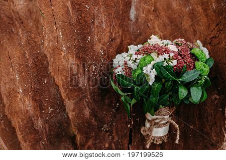 Rustic wedding bouquet with different flowers and greens on wooden background. Top view.