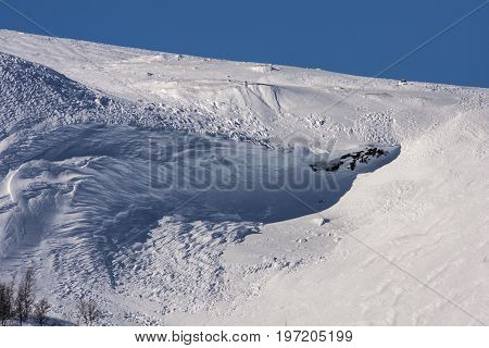 Rocks, cliffs on a mountain slope. Winter, snow and snow-pack.