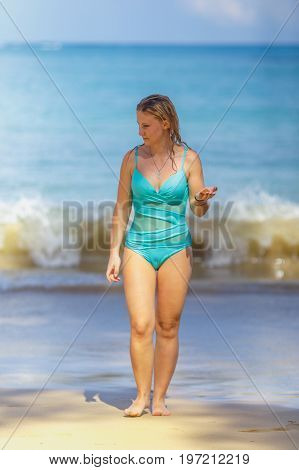 the girl in blue comes from the sea to the sandy beach