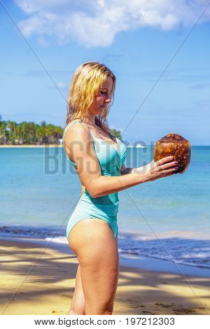 Young girl holding coconut on the beach