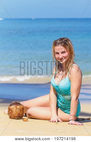 young pretty girl sitting on the beach with coconut
