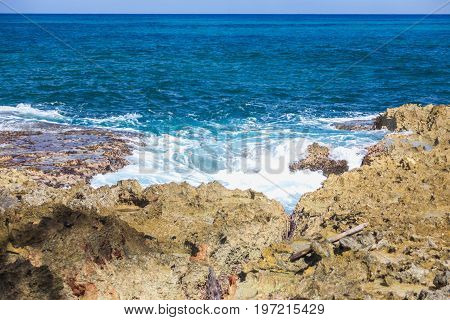 Foaming stormy sea and rocky shore in sunny weather