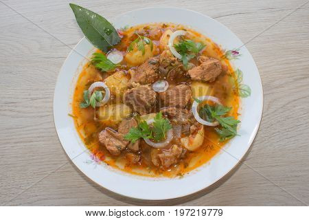 Delicious veal stew soup with meat and vegetables on wood table. Traditional goulash soup with potatoes and beef meat