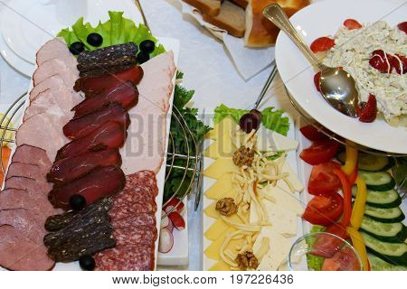 The dinner food table - top view. A delicious hearty meal of gourmet. Many dishes with appetizers on a white tablecloth. European cuisine for consumers.