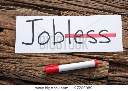 Closeup of jobless text on paper with strike on less word by marker on wood