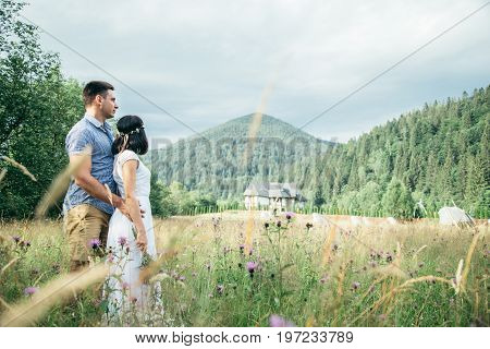 couple in love walking in feild with beautiful view on moutains, man hug woman