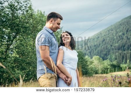 couple in love walking in feild with beautiful view on moutains, man hug woman