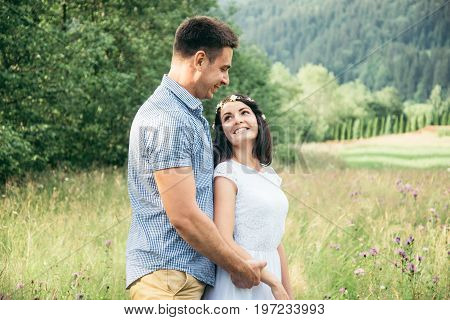 couple in love walking in feild with beautiful view on moutains, man hug woman