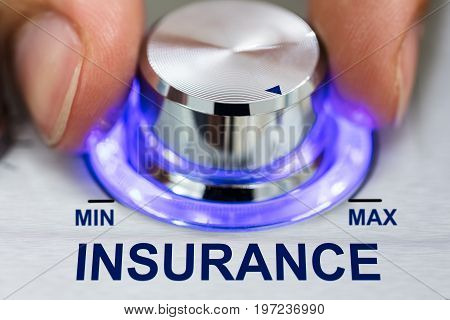 Cropped image of hand turning illuminated metallic knob by insurance text