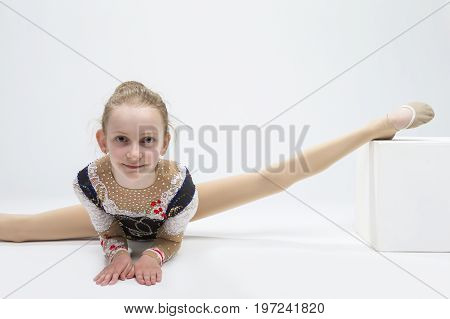 Sport concepts and Ideas. Young Caucasian Female Rhythmic Gymnast Athlete In Professional Competitive Suit Doing Split Exercise While Posing in Studio Against White. Horizontal Image Composition