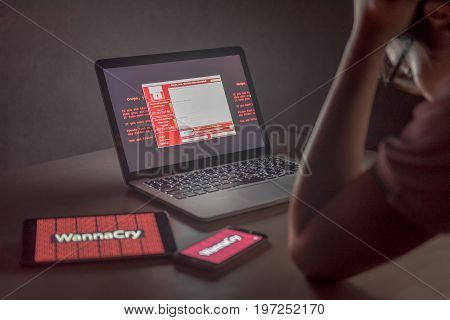 Young Asian male frustrated confused and headache by WannaCry ransomware attack on desktop screen notebook and smartphone cyber attack internet security concept