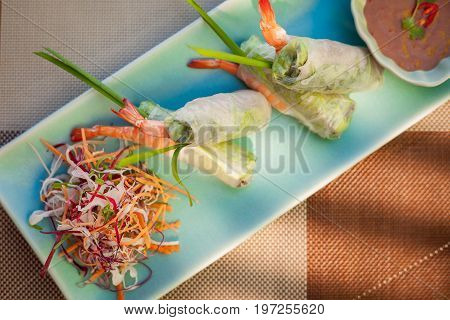 Springroll with vegetables and prawn served with salad and sauce. Vietnam asian cuisine on wooden table