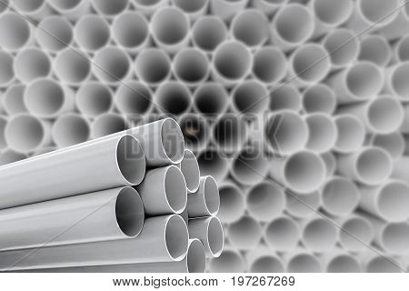 Gray PVC pipes stacked in warehouse .