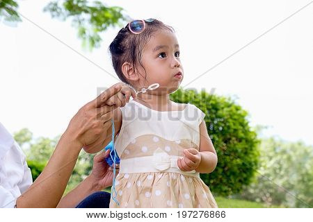 Happy child blowing soap bubbles in spring park with lens flares