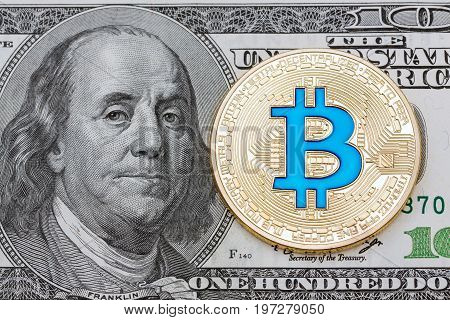 Golden cryptocurrency blue bitcoin on hundred dollar banknote background. High resolution photo.
