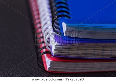 Several multi-colored notebooks on a spiral on a black background