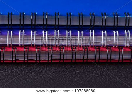Several multi-colored notebooks on a spiral on a black background