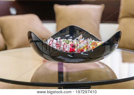 Close up modern plastic bowl with candies on table