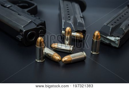 9 mm Pistol, bullets and magazine on drak background. Gun isolated