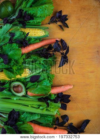 Vegetable Background With Copy Space. Lettuce, Basil, Three Carrots, Two Corns And Half Avocado On W