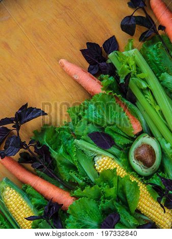 Vegetable Background With Copy Space. Lettuce, Basil, Three Carrots, Two Corns And Half Avocado On W