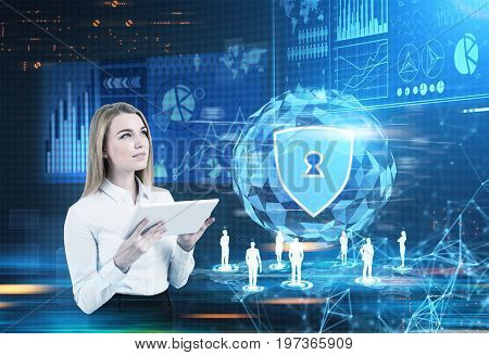 Inspired blonde businesswoman in a white blouse is holding a tablet computer while standing against a glowing security shield hologram. Blue. Toned image mock up double exposure