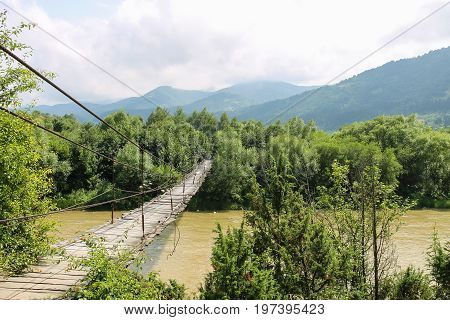 Suspended wooden bridge across Schodnica river in Carpathians Ukraine